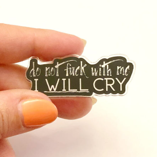 Close up of fingers holding an I will cry pin